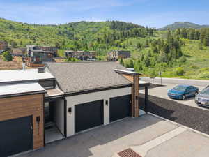 Modern home with a forest view, a shingled roof, and a mountain view