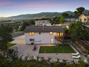 Rear view of property with a patio area, a deck with mountain and valley view, stairs, and a shingled roof