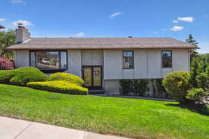 View of front of property with a chimney and a front lawn