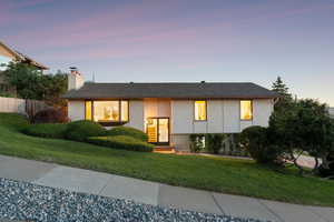 Front exterior featuring a chimney and brick siding at sunset
