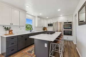 Kitchen with appliances with stainless steel finishes, a breakfast bar area, white cabinets