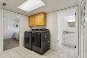 Laundry room featuring washer and dryer, light tile patterned flooring, cabinet space