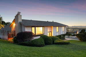View of front facade featuring a chimney and roof with shingles and valley views