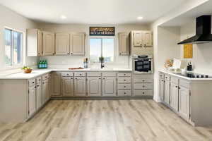 Kitchen with stainless steel oven, wall chimney exhaust hood, a sink, black electric stovetop, and light wood finished floors