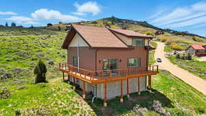 Back of house with a deck with mountain view and dirt driveway