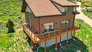 Rear view of house with roof with shingles, a wooden deck, and dirt driveway