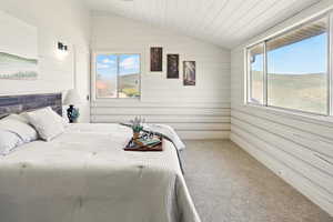 Carpeted bedroom with vaulted ceiling and wood walls