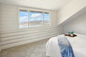 Carpeted bedroom with wood walls, lofted ceiling, and a water view