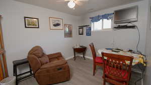 Home office with a ceiling fan, light wood-style flooring, and baseboards