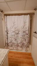Full bath featuring vanity, wood finished floors, shower / bath combo with shower curtain, and a drop ceiling