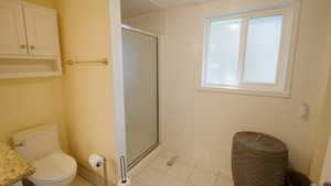 Full bath with a stall shower, tile patterned floors, and toilet