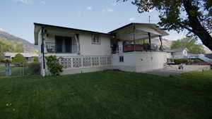 Back of property featuring a mountain view, a balcony, a patio, and a gate