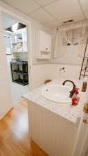 Bathroom with a paneled ceiling, vanity, a wainscoted wall, and wood finished floors