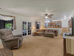 Living area with french doors, carpet floors, and ceiling fan
