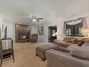 Carpeted living area featuring ceiling fan and a fireplace