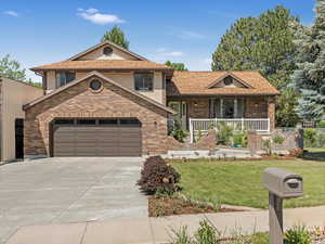 Split level home with brick siding, concrete driveway, a front yard, covered porch, and a garage