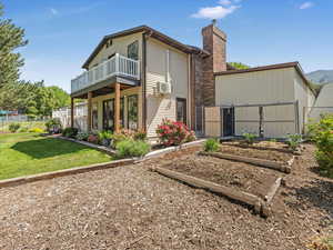 Back of house featuring a garden, a chimney, a balcony, and cooling unit