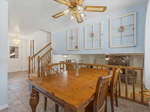 Dining room featuring a ceiling fan, a chandelier, a brick fireplace, and stairs