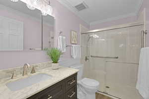 Bathroom featuring toilet, vanity, a shower stall, ornamental molding, and wood finished floors