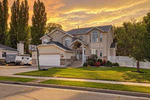 Traditional home with stucco siding, stone siding, and driveway