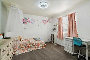 Bedroom featuring dark colored carpet and baseboards
