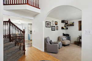 Living room featuring arched walkways, baseboards, stairway, and wood finished floors