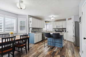 Kitchen with appliances with stainless steel finishes, a center island, white cabinetry, a sink, and dark wood finished floors