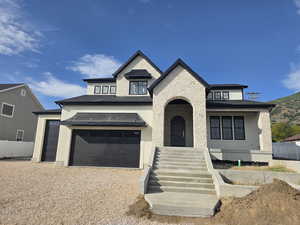 View of front of house with natural stone, fine sand stucco, an attached garage, and a mountain view.