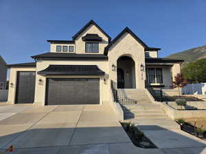 View of front of property featuring stone siding, driveway, stucco siding, stairway, and a mountain view