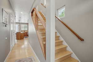 Staircase with wood finished floors, baseboards, recessed lighting, and a textured ceiling