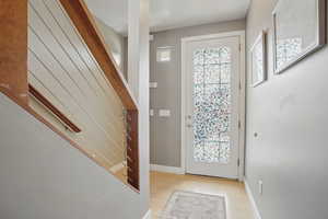 Foyer with light wood-style flooring, stairs, and baseboards