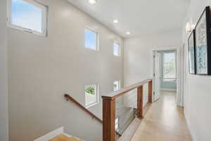 Hallway featuring an upstairs landing, plenty of natural light, baseboards, light wood-type flooring, and recessed lighting