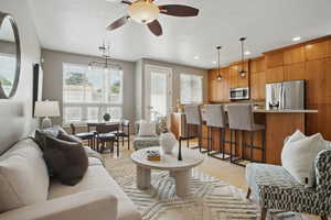 Living area with a textured ceiling, a ceiling fan, light wood-style floors, and recessed lighting