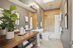 Full bath with baseboards, shower / tub combo, a sink, and toilet