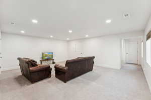 Living area with light carpet, recessed lighting, and baseboards
