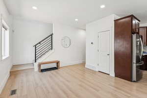 Unfurnished living room featuring stairway, light wood-style floors, baseboards, and recessed lighting