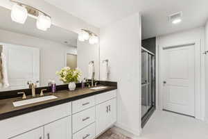 Bathroom featuring double vanity, a shower stall, tile patterned floors, and baseboards