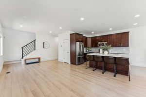Kitchen with appliances with stainless steel finishes, light countertops, tasteful backsplash, recessed lighting, and light wood-type flooring