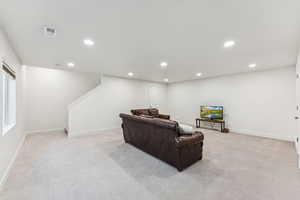 Living area with light colored carpet, recessed lighting, stairs, and baseboards