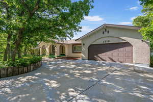 View of front of home with concrete driveway, stucco siding, an attached garage, and covered porch
