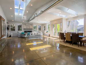 Living area featuring concrete floors, plenty of natural light, recessed lighting, a skylight, and a brick fireplace