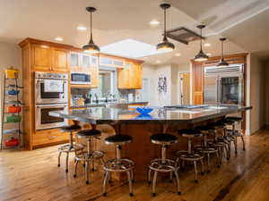 Kitchen featuring appliances with stainless steel finishes, a spacious island,Cherry wood cabinets a kitchen bar, and decorative light fixtures
