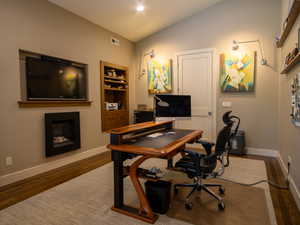 Office area featuring wood finished floors, Fireplace, built in features, and lofted ceiling
