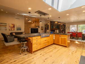Kitchen featuring stainless steel gas stovetop, open floor plan, recessed lighting, Natural Cherry wood cabinets, and a breakfast bar
