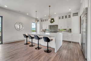 Kitchen with decorative backsplash, light countertops, light wood-style floors, white cabinets, and recessed lighting