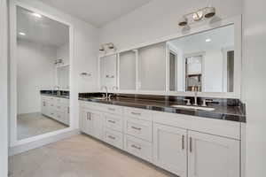 Full bathroom featuring double vanity, marble look tiles, and recessed lighting