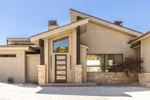 Property entrance featuring a chimney and stone siding