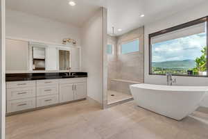 Full bathroom featuring a walk in shower, a freestanding bath, vanity, and recessed lighting