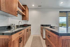 Kitchen featuring open shelves, a sink, dark stone counters, a peninsula, and recessed lighting