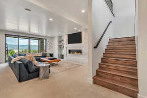 Carpeted living area with a fireplace, stairway, recessed lighting, and built in features